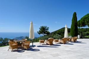 un grupo de sillas y mesas con sombrillas en The Unique Villa with Magnificent sea view, en Èze