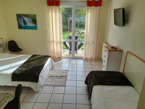 a bedroom with two beds and a sliding glass door at Hotel de l'Ile d'Amour in Langeac