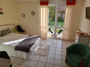 una camera con un letto e una sedia e una finestra di Hotel de l'Ile d'Amour a Langeac