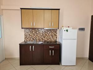 a kitchen with brown cabinets and a white refrigerator at Studio Eno Ksamil in Ksamil +33 photos