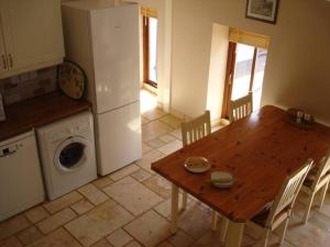 a kitchen with a wooden table and a kitchen with a washing machine at Creedy Meadow Barn in Crediton