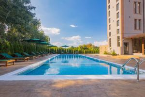 a swimming pool with chairs and umbrellas next to a building at Lecardo Hotel in Aheloy