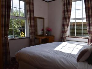 a bedroom with a bed and two large windows at Hillview in Crooklands