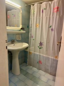 baño con lavabo y cortina de ducha con flores en Vintage-style 2 bedroom apartment at Katechaki en Atenas