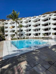 um grande edifício de apartamentos branco com uma piscina em El Cardenal em Playa del Cura