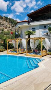 a villa with a swimming pool in front of a house at Bybassios Orhaniye in Orhaniye