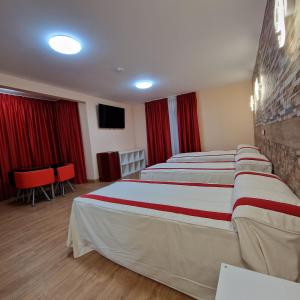 Habitación de hotel con 2 camas y cortinas rojas en Gavilanes 2 TOLEDO, en Toledo
