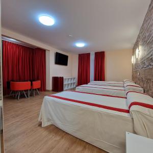 a hotel room with two beds with red curtains at Gavilanes 2 TOLEDO in Toledo