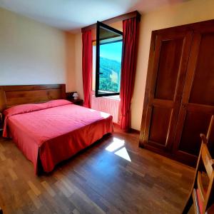 a bedroom with a red bed and a window at Hotel Bellavista in Abetone