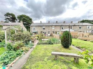 a garden with a bench in front of a building at Impressive 3 bed cottage by the river in Stanhope in Stanhope