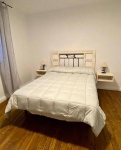 a bedroom with a large white bed with two lamps at Casa Buitreras in El Colmenar