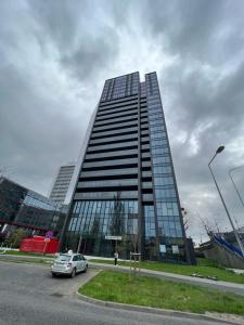 un edificio alto con un coche aparcado delante de él en Towarowa - Milionowa 39 Check-in 24H en Poznan