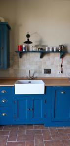 uma cozinha com armários azuis e um lavatório branco em Podere Campiano em Volterra