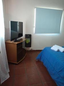 1 dormitorio con 1 cama y escritorio con TV en Departamento La Trinidad en Merlo