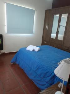 1 dormitorio con 1 cama azul y 2 toallas en Departamento La Trinidad en Merlo