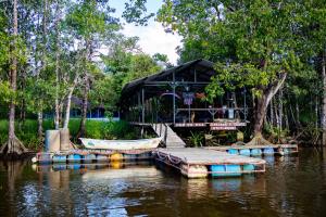 a house on the water with a boat in the water at Oso de Osa in Sierpe