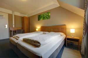 a bedroom with a large bed with white sheets at Gasthaus Mooshäusl in Hebertshausen