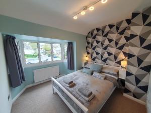 a bedroom with a large bed with a geometric wall at Yucca cottage in Kendal