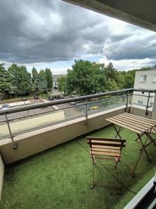 d'un balcon avec un banc et une table sur la pelouse. dans l'établissement Appartement sans vis à vis à 2 min de la rocade, à Rennes