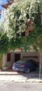 a car parked under a flowering tree in front of a house at Στούντιο Κέντρου Άνω πόλης Πάτρας in Patra