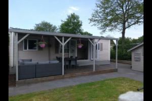 a screened in patio with a couch and a table at Chalet te huur op *****camping Terspegelt 4 personen in Eersel