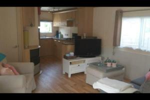 a living room with a television and a kitchen at Chalet te huur op *****camping Terspegelt 4 personen in Eersel