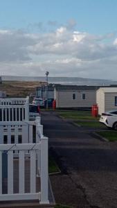 a white fence in front of a street with buildings at Crimdon dene bay view holiday home NO SMOKING NO PETS in Durham