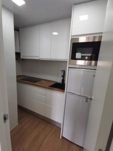 a kitchen with white cabinets and a refrigerator at Ático en Calella a 7 minutos de la playa in Calella +5 photos