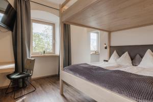 a bedroom with a bed and a chair and two windows at Gasthof Pension Knapp in Strass im Zillertal
