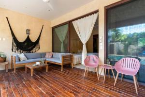 ein Wohnzimmer mit einem blauen Sofa und rosa Stühlen in der Unterkunft Casa Esperanza Tulum Private Pool in Tulum