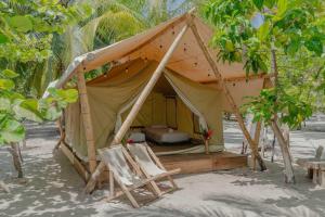 una tenda con sedie e un letto nella sabbia di Manoush Beach a Buritaca