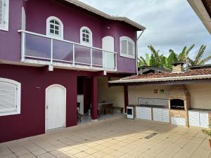 ein lila Haus mit einem Balkon und einer Terrasse in der Unterkunft CASA NO CENTRO DE BERTIOGA in Bertioga