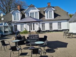 ein Haus mit Stühlen, Tischen und einem Sonnenschirm in der Unterkunft Trandafir Guesthouse in Egtved