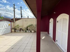 ein rotes Haus mit weißen Türen und einem Innenhof in der Unterkunft CASA NO CENTRO DE BERTIOGA in Bertioga