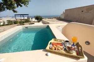 a tray of food on a table next to a swimming pool at Dreamer's Secret villa 2 in Emporio Santorini