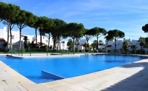 una gran piscina azul con árboles en el fondo en Pareado en Loma Sancti Petri a 900 m de la playa de La Barrosa en Chiclana de la Frontera