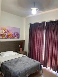 een slaapkamer met een bed en een raam met rode gordijnen bij Prince Hotel Fier in Fier
