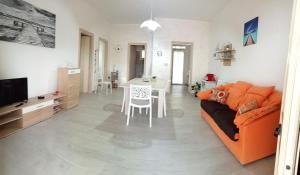 uma sala de estar com um sofá laranja e uma mesa em Casa Paky em Punta Prosciutto