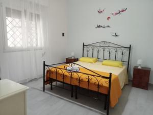 una camera da letto con letto nero e cuscini gialli di Casa Paky a Punta Prosciutto