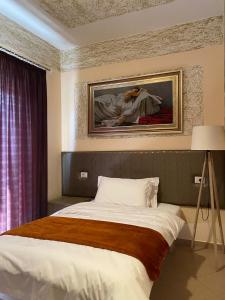 een slaapkamer met een bed en een schilderij aan de muur bij Prince Hotel Fier in Fier