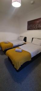una camera con tre letti con coperte gialle di Sheffield City Suites a Manor