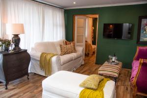 a living room with green walls and white furniture at La Lupa Nera in Knysna