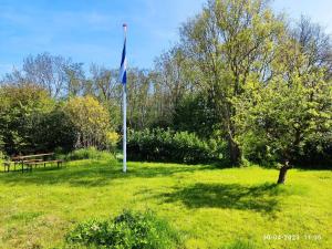 una bandera en un poste en un campo con un banco en mini-camping 't Bergje en Serooskerke