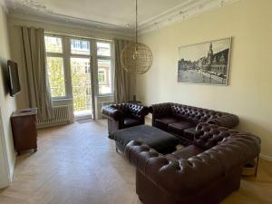 ein Wohnzimmer mit 2 Ledersofas und einem TV in der Unterkunft Ruhige&charmante Altbauwohnung in Leipzig