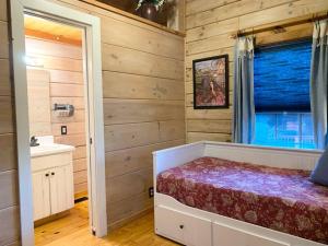 een slaapkamer met houten wanden, een bed en een raam bij Log Cabin Walkable to Lake Lure & Chimney Rock - Blue Skies in Lake Lure