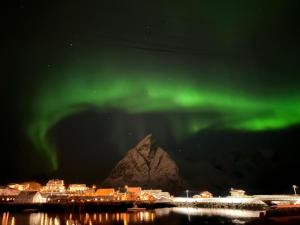 an aurora over a city with a mountain in the background at Rostad Retro Rorbuer in Reine