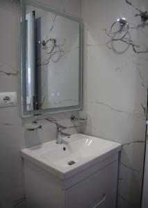 Baño blanco con lavabo y espejo en Sunset Cottage 1, en Ksamil