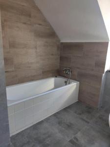 a white bath tub in a bathroom with wooden walls at Holiday House Dąbrówno in Dąbrówno