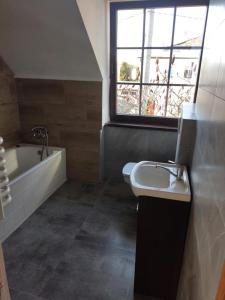 a bathroom with a sink and a bath tub and a window at Holiday House Dąbrówno in Dąbrówno