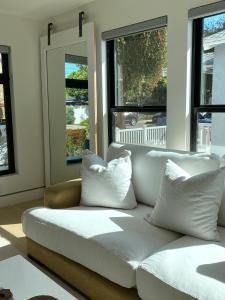 Sofá blanco sentado en una habitación con ventanas en Bright modern new coastal home with inspiring details in Santa Monica, en Los Ángeles